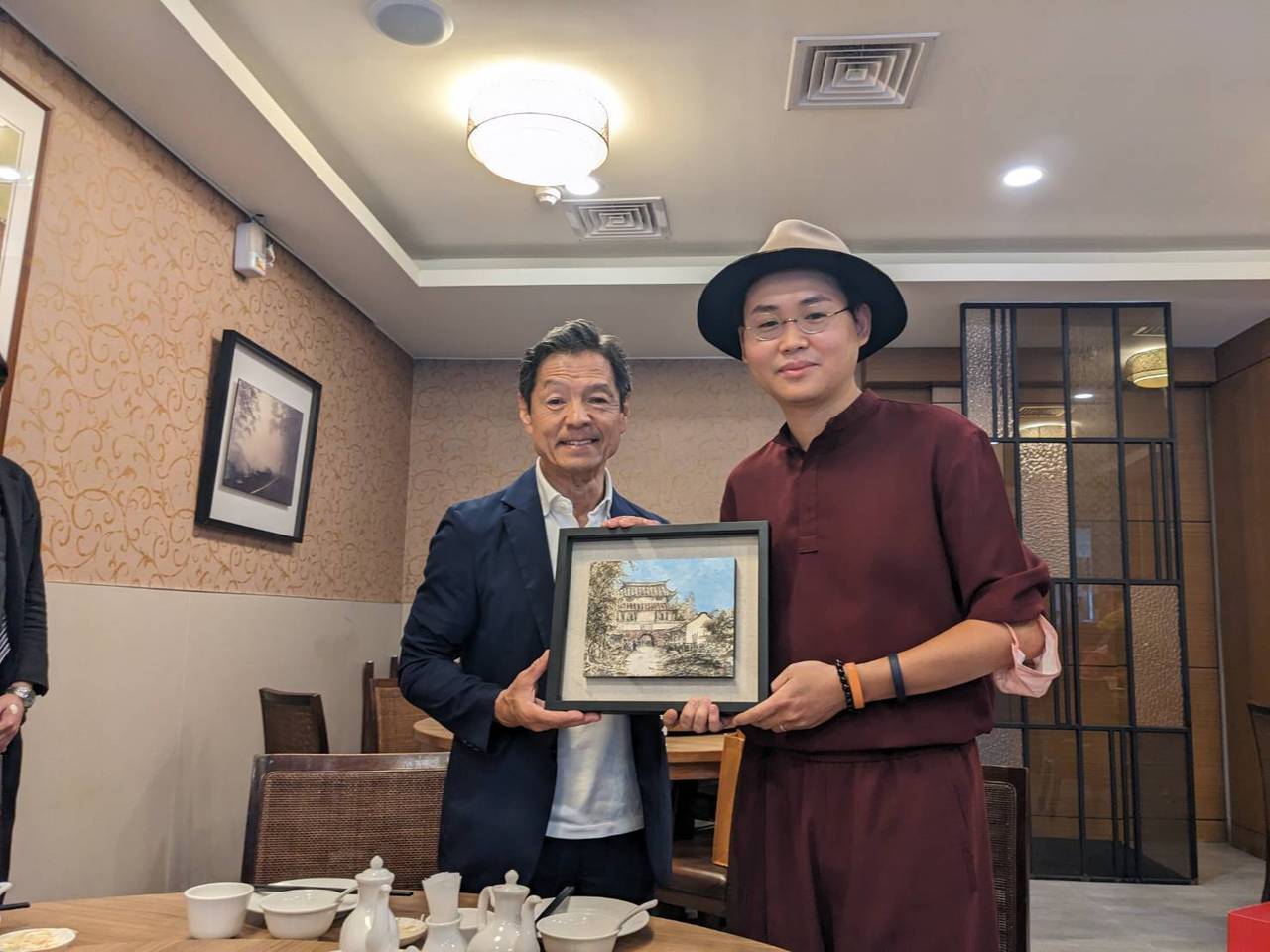 台南年輕畫家邱郁仁贈送畫作給菊池市代表團,此畫是由特殊方式以茶調入墨色,因此散發...