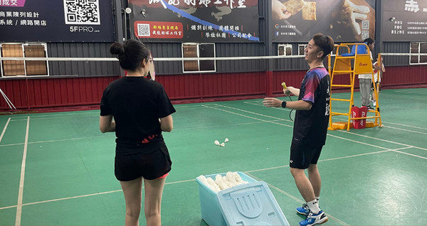 教練耐心在學生旁講解羽球技巧